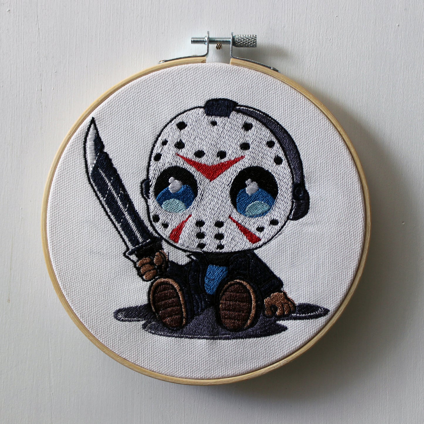 Embroidery hoop with a Jason holding a knife on a white background.
