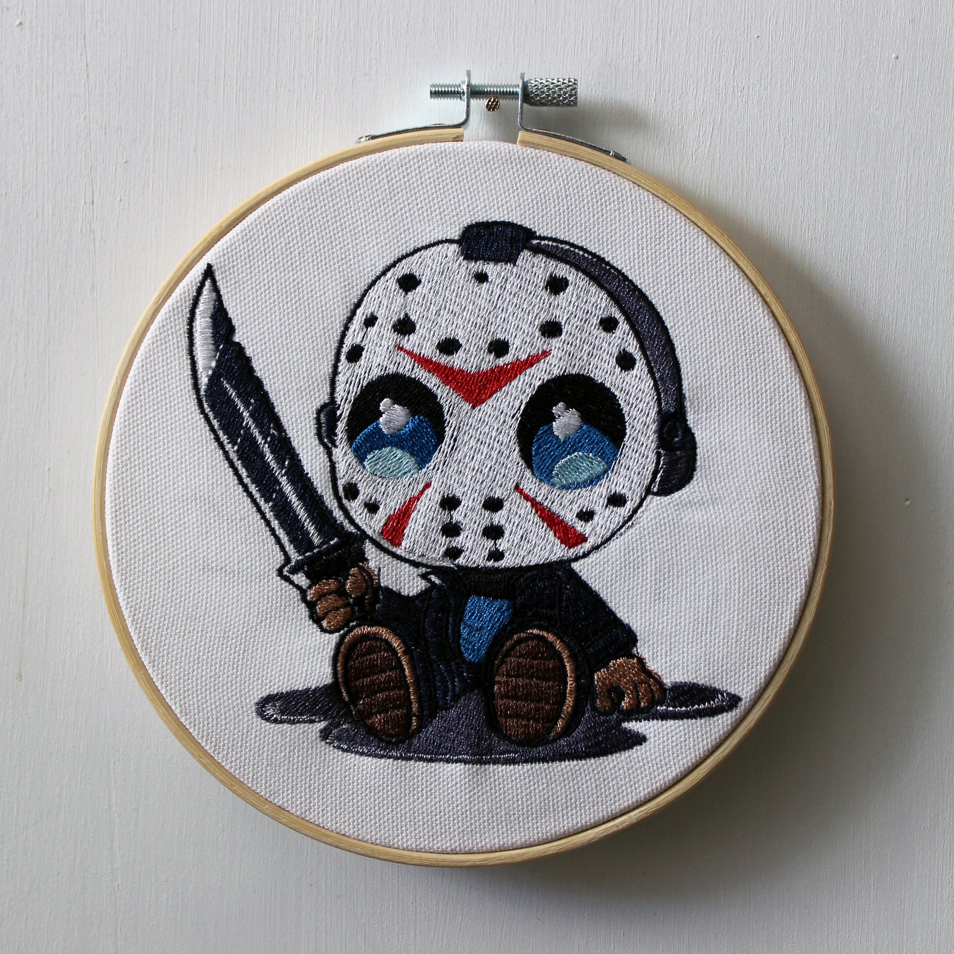 Embroidery hoop with a Jason holding a knife on a white background.
