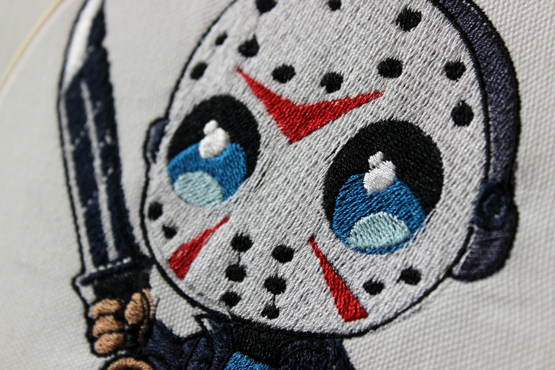 Embroidered patch of Jason with a mask and knife on a white background.
