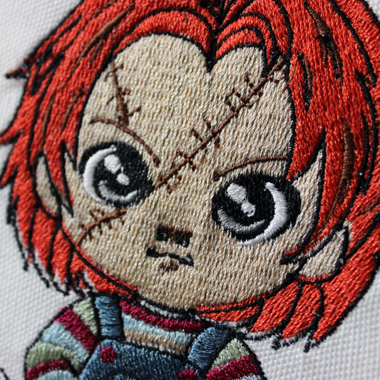 Embroidery of Chucky with red hair and a neutral expression on a white background.