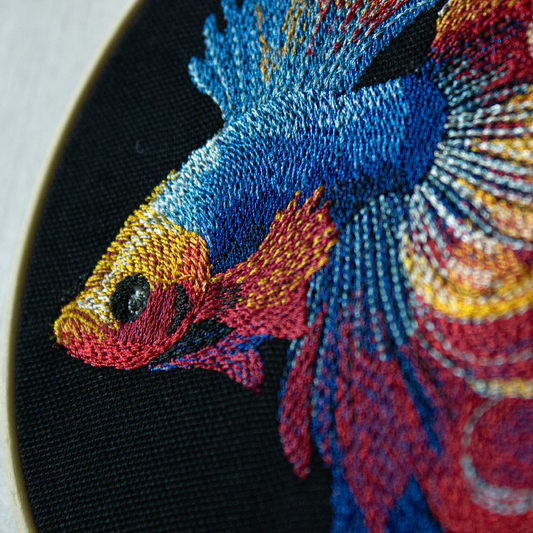 Embroidery of a colorful fish on a black background.