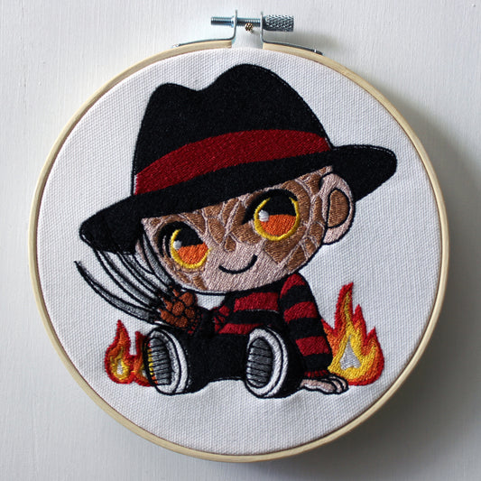 Embroidery of Freddy Krueger with a hat and flames in an embroidery hoop.