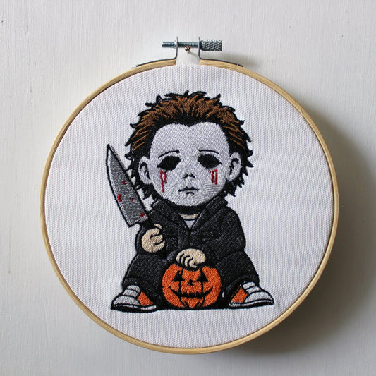 Embroidery hoop with Michael Myers holding a knife and pumpkin on a white background.