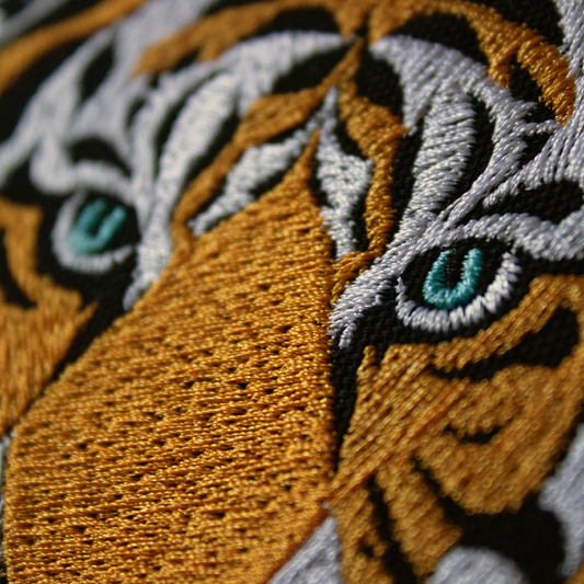 Close-up of an embroidered tiger design with detailed eyes.